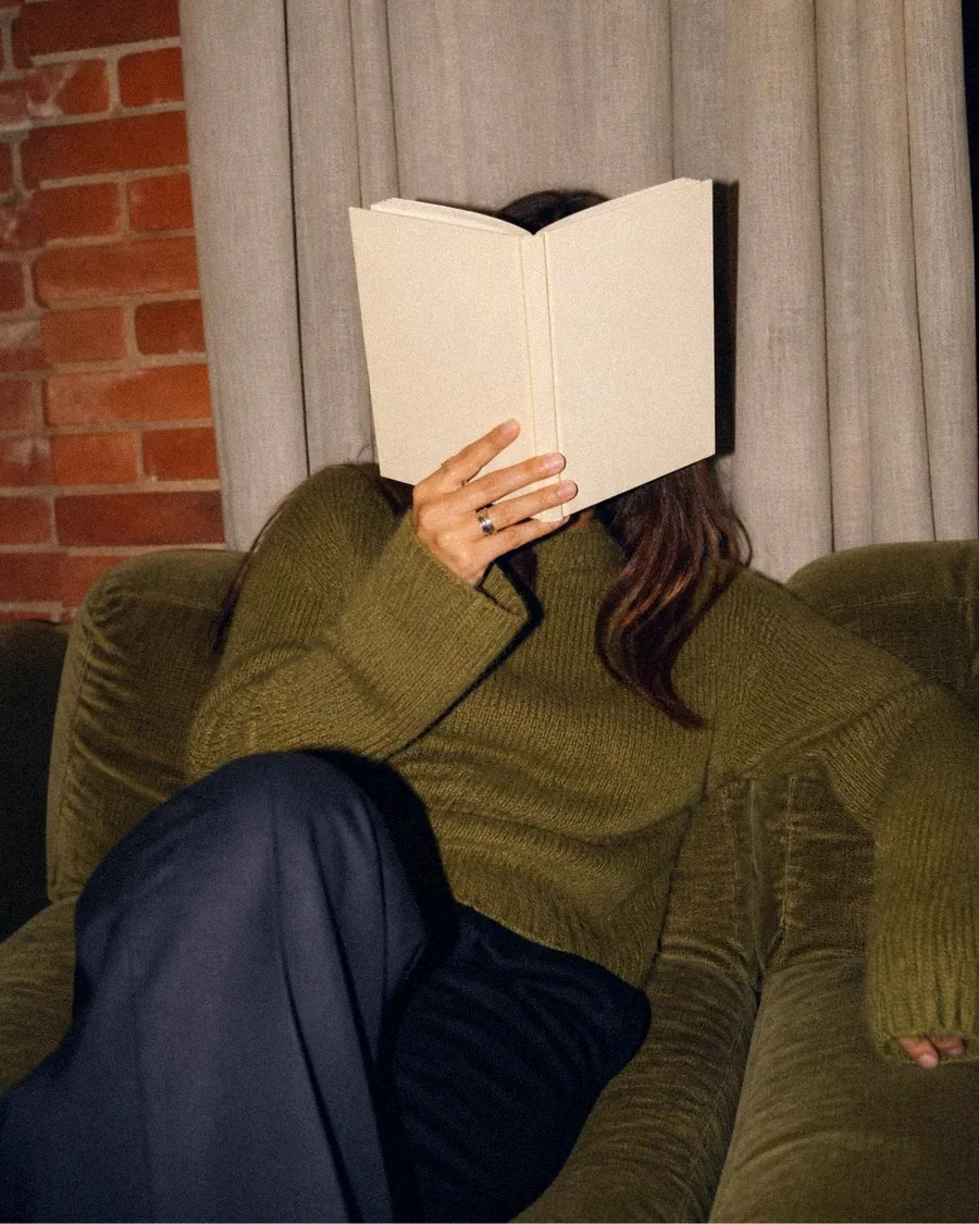 Étudiante lisant, le visage caché derrière un livre