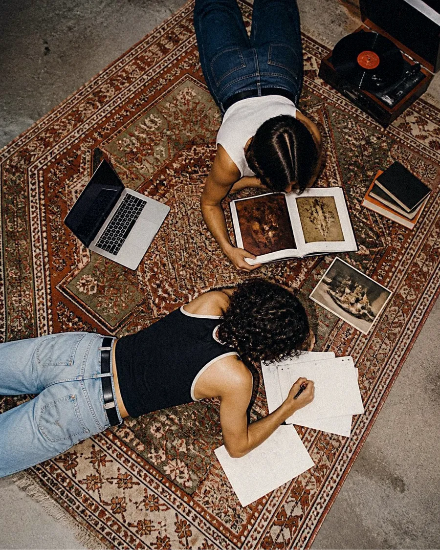 Deux étudiants travaillant au sol sur un tapis, vue du dessus